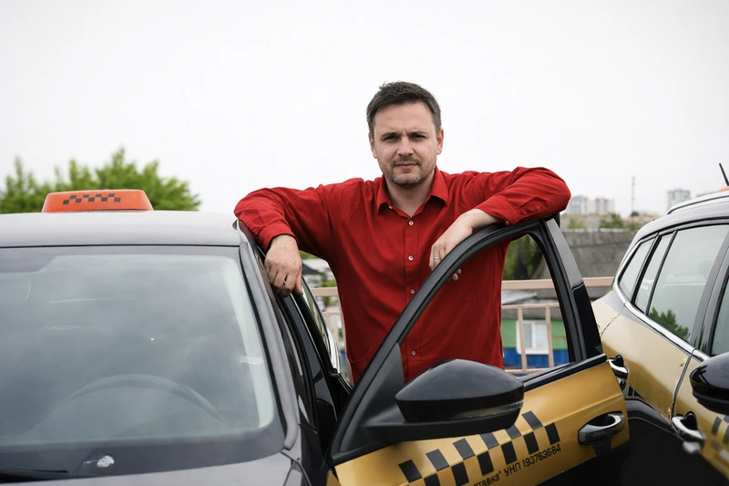 Водитель рядом с автомобилем такси